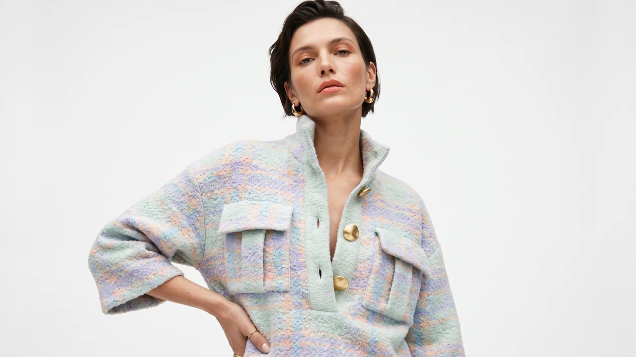 A model in a pastel tweed pullover with gold buttons